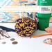 A purple and yellow swirl print water bottle bag is displayed with a 40 ounce Stanley Quencher tumbler, money, eyeglasses & a pencil.